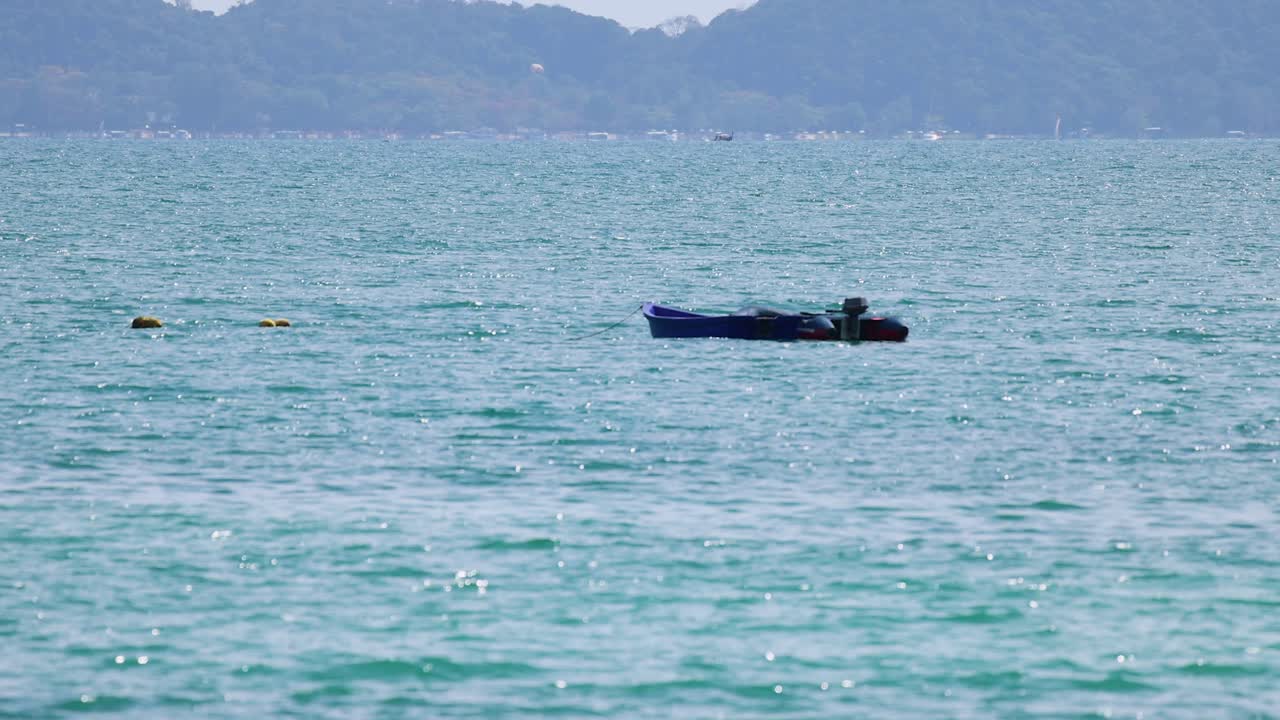A long-tail boat glides across the turquoise ocean near Phuket, Thailand, under clear skies. Calm and serene atmosphere
