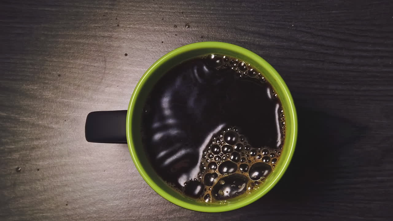 Overhead slow motion of pouring coffee into the ceramic mug