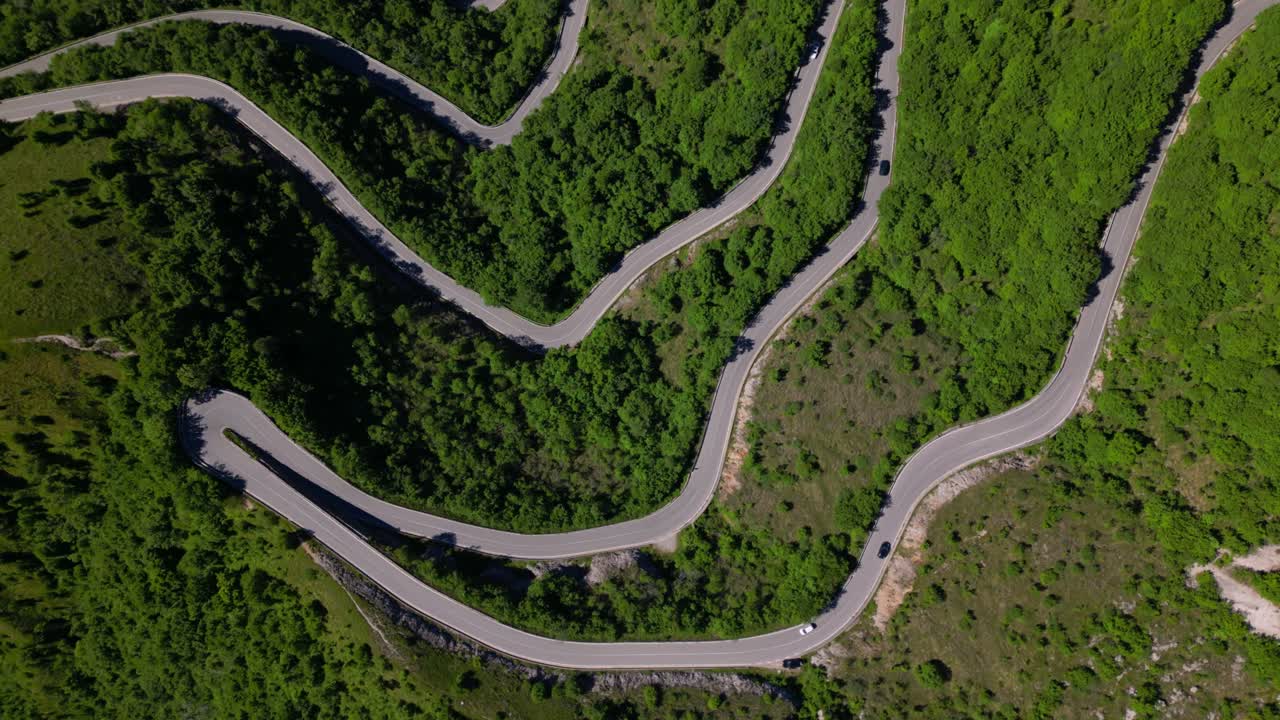 Top-down view of a serpentine mountain road weaving through dense green vegetation. Shot at Selvino, Italy (Selvino, Italia)