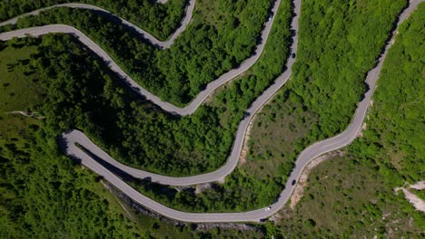 top-down view of a serpentine mountain road weaving through dense green vegetation. shot at selvino, italy (selvino, italia)