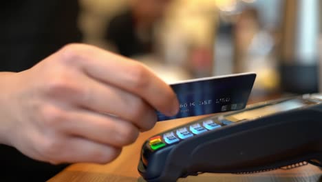 a close-up of a payment terminal in use: capturing a hand interacting with the device as a card is prepared for contactless payment processing