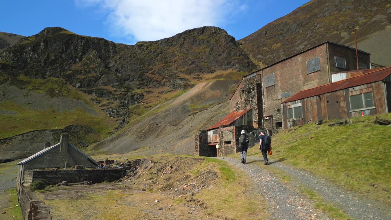Escursionisti che si dirigono verso gli impianti minerari abbandonati a Coledale Beck nel Distretto dei Laghi inglese, Cumbria.