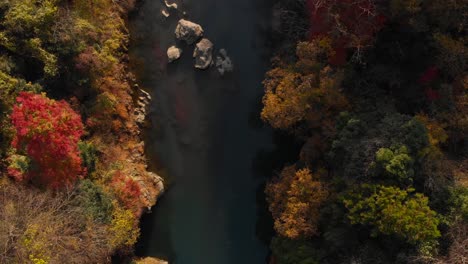 slow aerial drone view looking down on river running through fall color valley