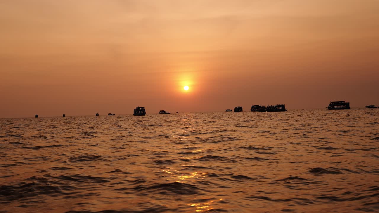 Golden sunset reflects on Tonle Sap water as distant boats float peacefully