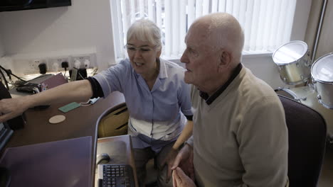 elderly man and caregiver looking at computer
