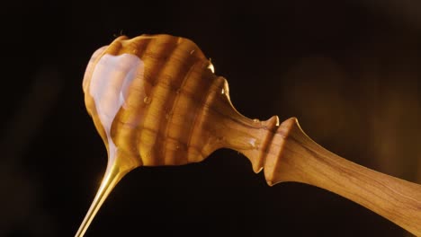 Static-shot-of-a-spinning-honey-spoon-on-which-honey-is-flowing-against-black-background