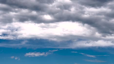 Weiche-Graue-Wolken-Bewegen-Sich-Am-Blauen,-Sonnigen-Himmel