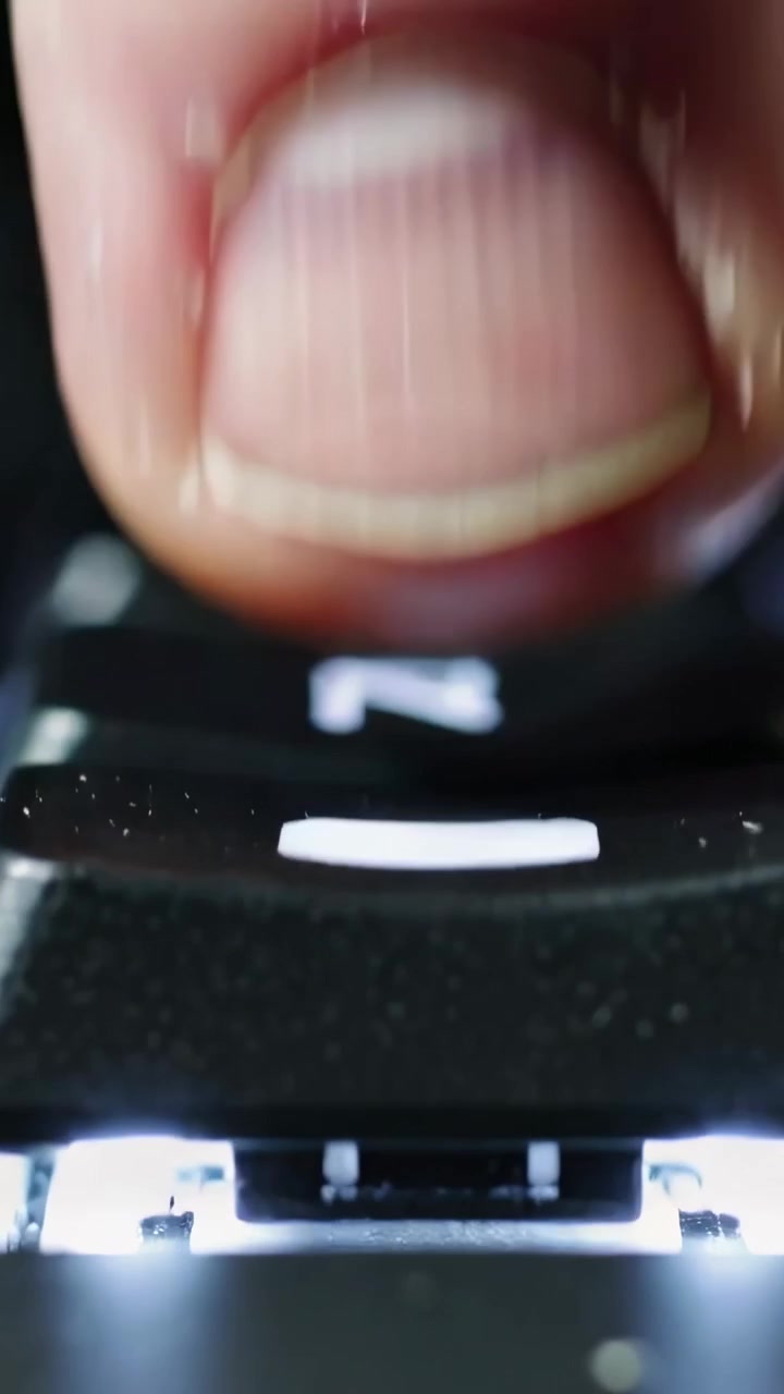 Video verticale: Un polpastrello che inizia a premere, tenendo un tasto contrassegnato di bianco su tasti retroilluminati con LED.