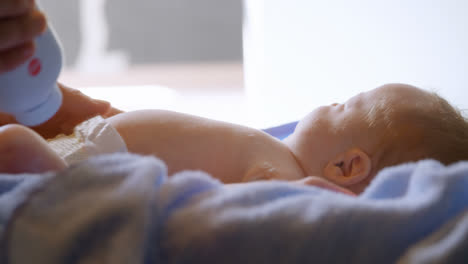 Mother-applying-powder-to-her-baby-boy-at-home-4k