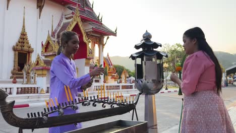 women praying at a buddhist temple in thailand