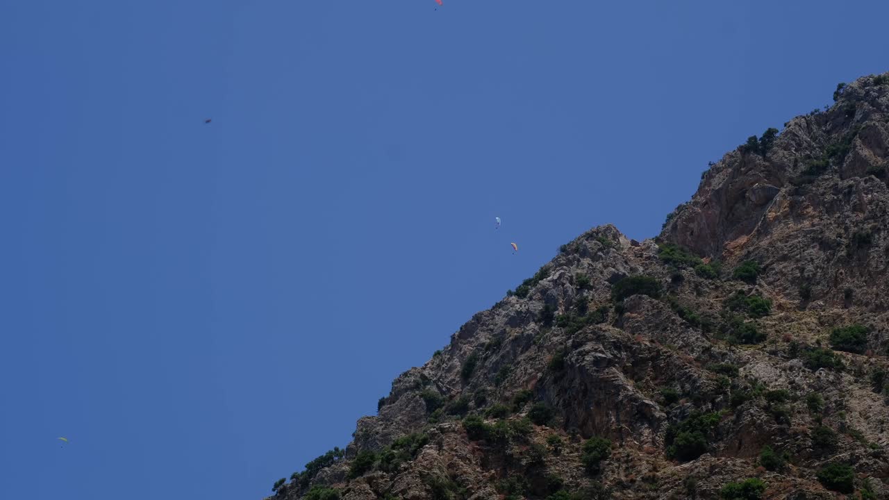 personas en parapente desde el costado de la montaña