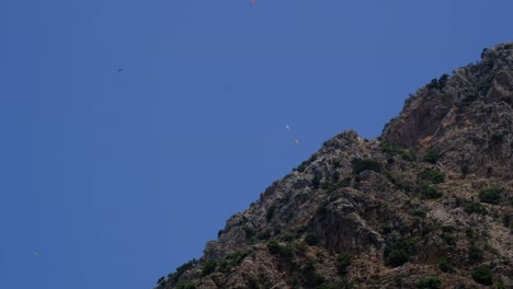 personas en parapente desde el costado de la montaña