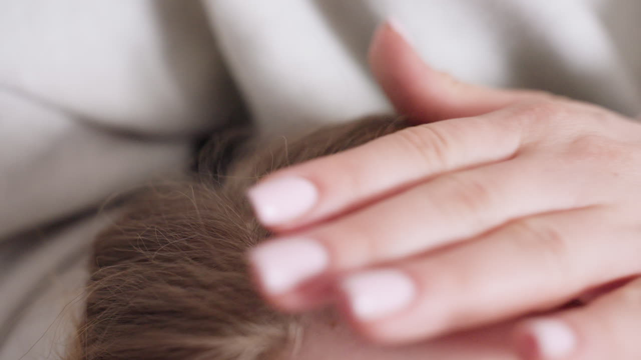 Close up of woman hand with neat manicure gently caressing child hair, expressing tenderness, affection, comfort, and emotional connection in serene family moment indoors with warm atmosphere of care
