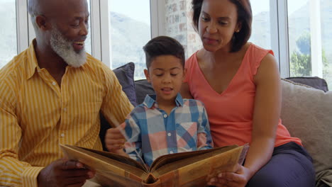 Mixed-race-multi-generation-family-looking-at-photo-album-in-living-room-at-home-4k