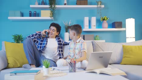 el hermano mayor hablando por teléfono molesta a su hermano menor, que está leyendo.
