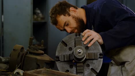 Metalsmith-checking-machine-parts-in-workshop-4k