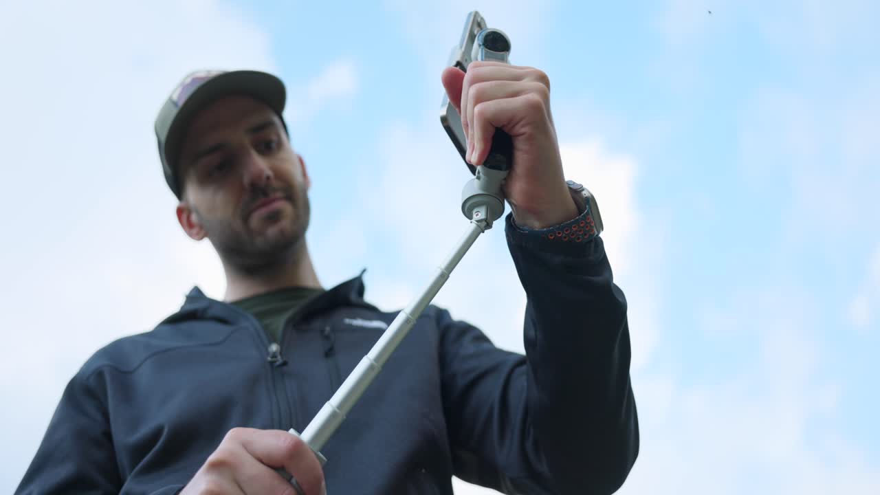 Man Using The Selfie Stick Of An Insta360 Flow Gimbal - Close Up