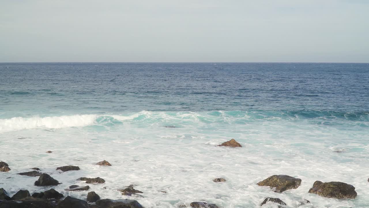 Atlantic Ocean waves crushing into the stone beaches of madeira island, Portugal.