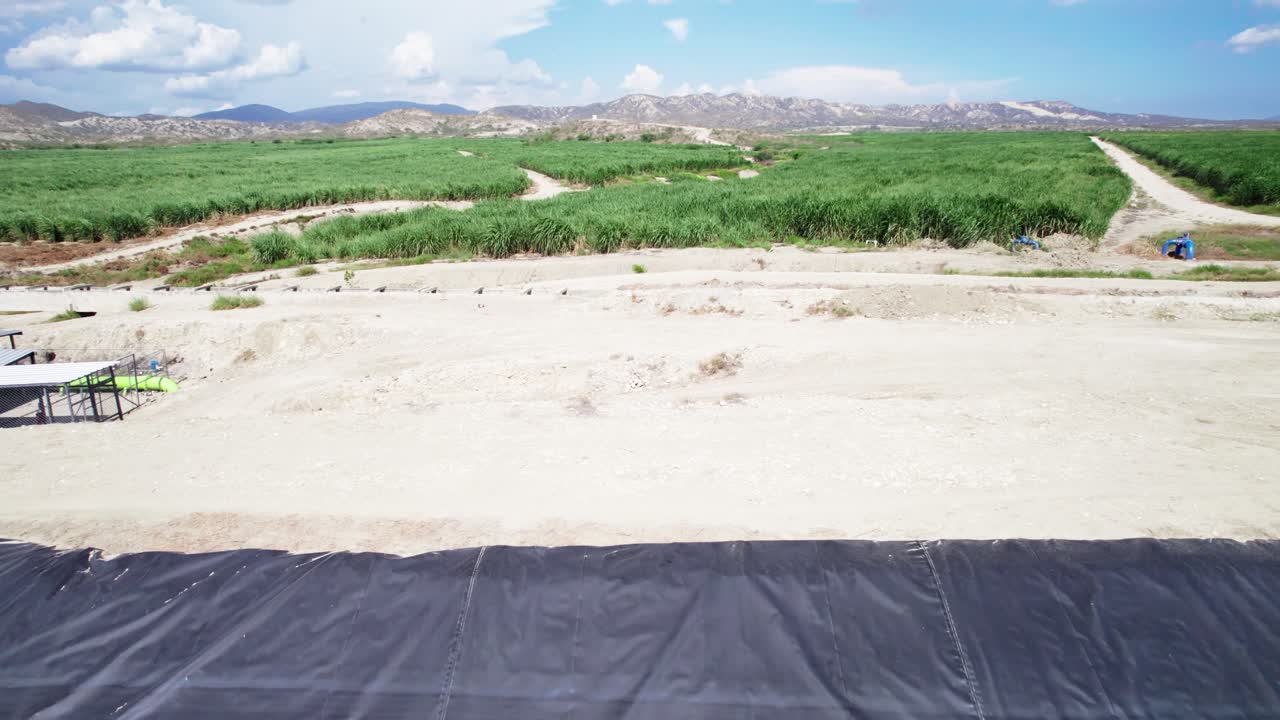 Zoom in drone view over a water reservoir used for drip irrigation systems, surrounded by agricultural fields in Barahona under daylight conditions
