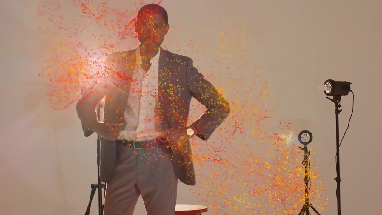 Male model sitting on red stool as left particle cloud appearing across him enhancing fashion shoot