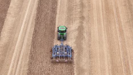 aerial view of a tractor in etchilhampton, uk, working the fields post-harvest with visible tire tracks on the soil