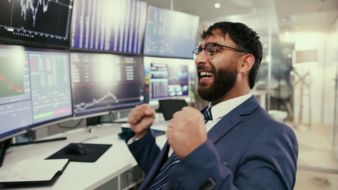 un hombre de negocios en un traje sonríe y mira las tablas en las pantallas de la computadora en una oficina