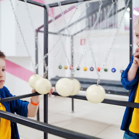 boys doing experiment with newton's cradle physics concept for education. museum of science