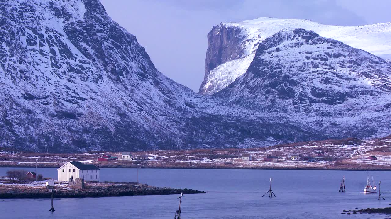 un barco de pesca se dirige a través de los fiordos en luz dorada en las islas árticas lofoten noruega