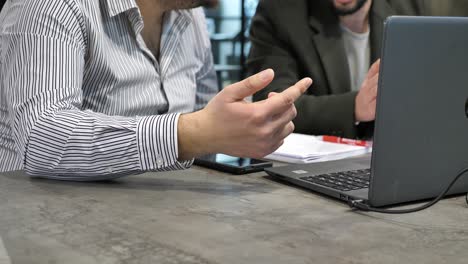 Two-unrecognizable-office-employees-discussing-problem-solution-by-laptop