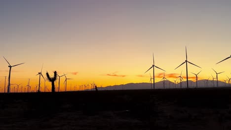 granja de aerogeneradores de silueta con cielos de puesta de sol de color naranja dorado