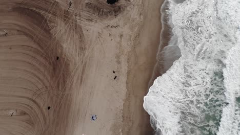 birdseye view drone footage of a beautiful beach with waves crashing against the soft white sand