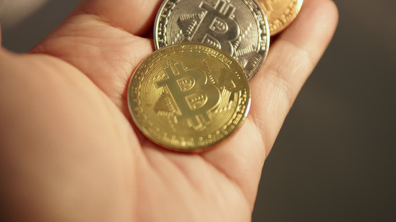 tres monedas de bitcoin se giran en la palma de la mano