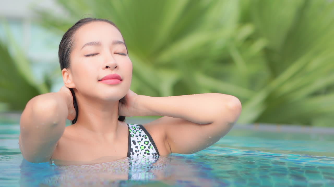 그녀의 얼굴에서 그녀의 젖은 머리를 밀어 수영장에서 아름다운 여자의 근접