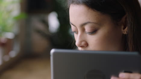 close up young hispanic woman using digital tablet computer in cafe drinking coffee enjoying watching online entertainment reading social media on portable device