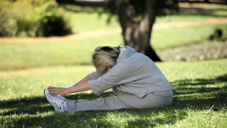 Old-woman-doing-warm-up-sitting-on-the-grass