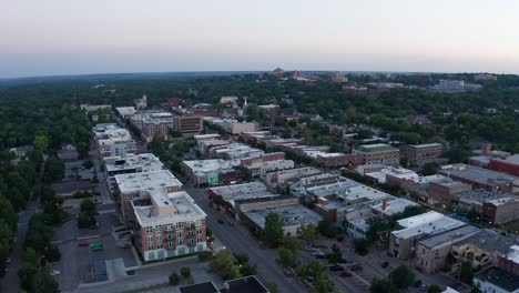 Toma-Aérea-De-Carro-Volando-Sobre-La-Calle-Massachusetts-En-El-Centro-De-Lawrence,-Kansas-Al-Atardecer