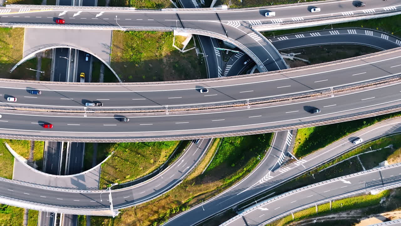 Complex traffic from linked highways. Aerial view shows a complex highway system with lanes and vehicles navigating interchanges in daylight