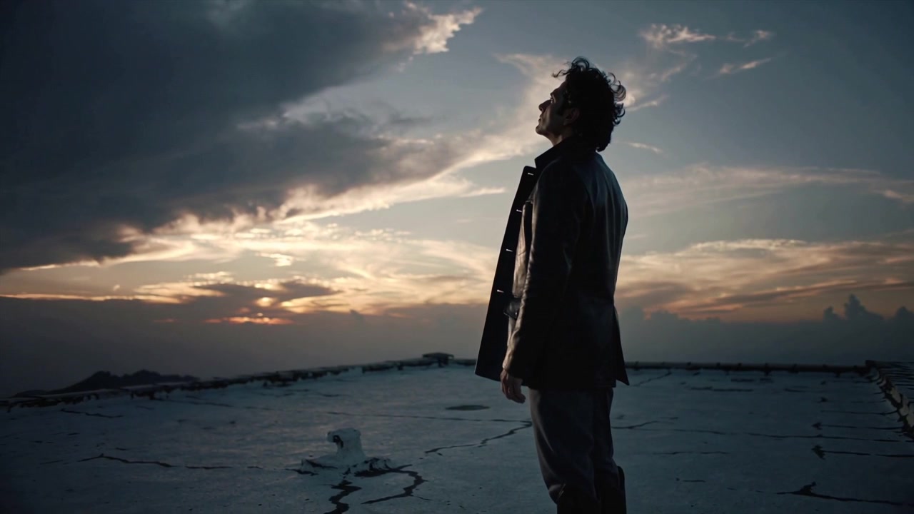 Uomo in piedi da solo su un tetto che guarda il tramonto.