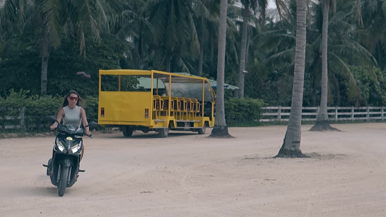 선글라스를 입은 검은 머리카락의 여성이 검은 모터사이클을 타고 있습니다.