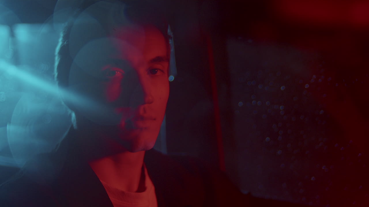 Portrait of Young Male Driver in Car at Night Red and Blue Lights