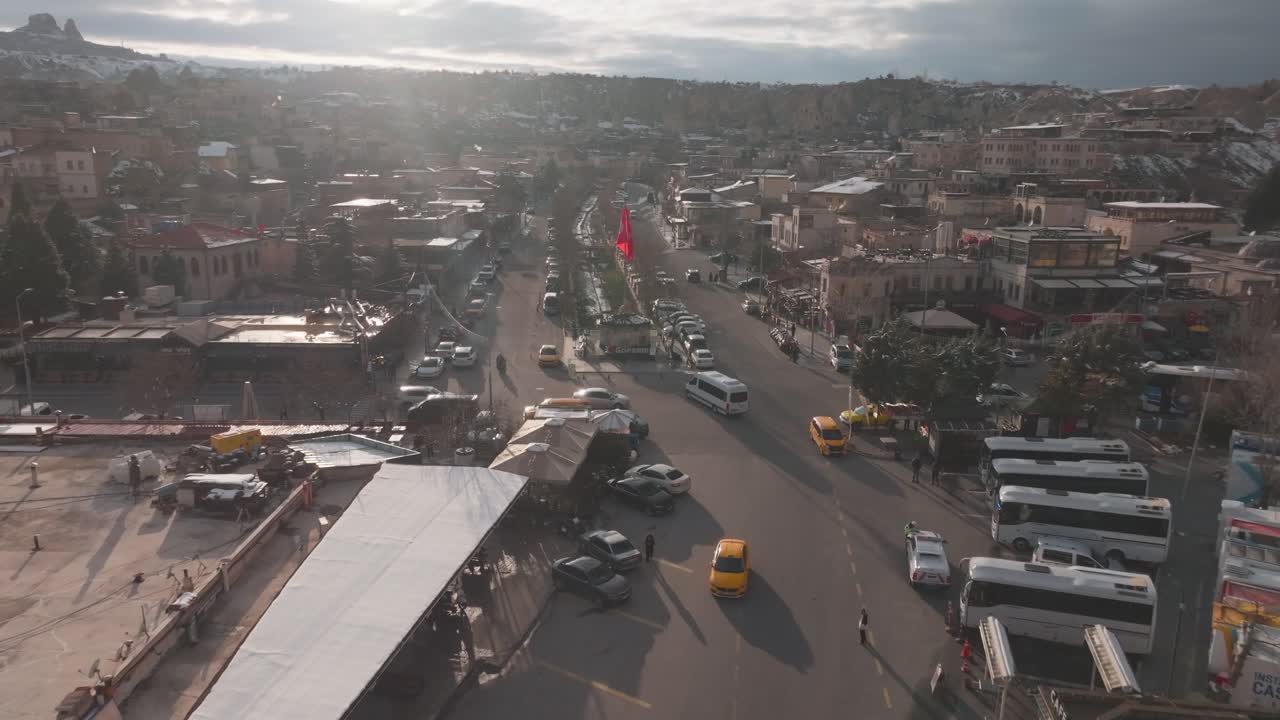 Kapadokya'daki Göreme kasabasının hareketli sokaklarını, park halindeki arabalarını ve eşsiz mimarisini altın saatte yakalayan yüksek açılı bir drone hava çekimi