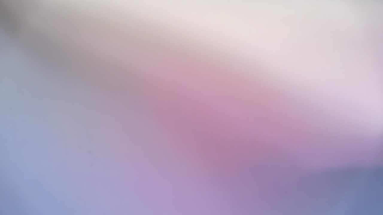Sweeping soft curved surface approaching lens inside room, camera capturing pastel fabric-like blur