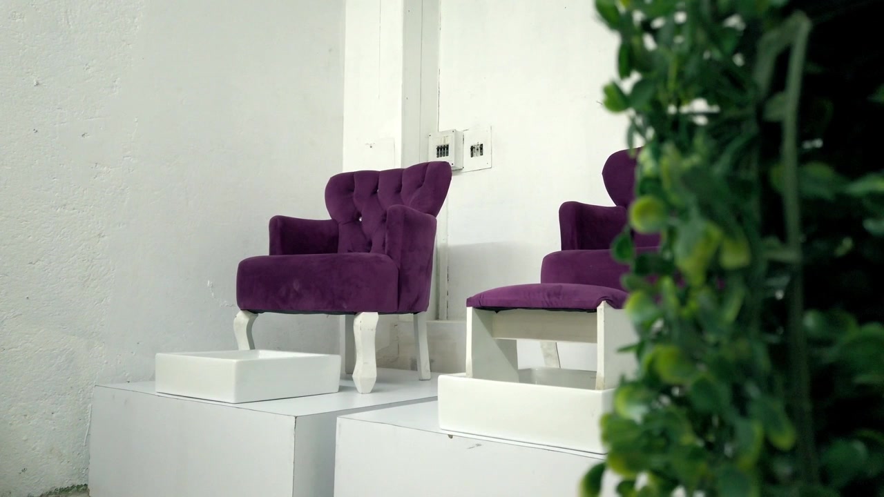 Vista di moderne poltrone viola esposte all'interno di uno showroom con interni minimalisti, con mobili eleganti, decorazioni bianche e design d'interni contemporaneo
