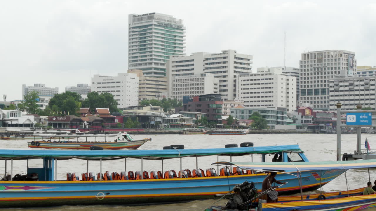 Passenger ferries of different sizes are cruising along the Chao Phraya River, a major waterway in the city of Bangkok, Thailand.