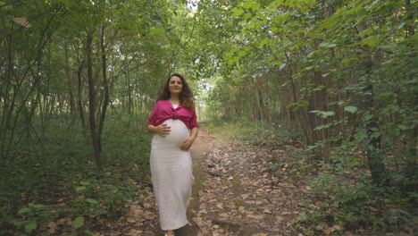 pregnant mom having workout going down forest trail, carefully avoiding branch