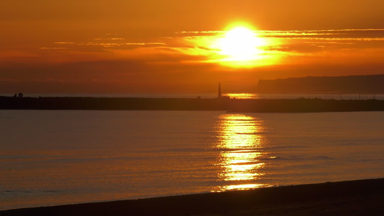Coastal seascape sunrise over calm sea and harbor wall
