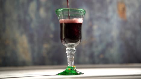 clip de vino tinto en bucle sin costuras que se vierte en un vaso rústico con fondo azul