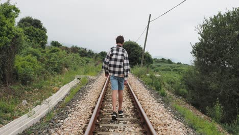 teenager walking on train tracks