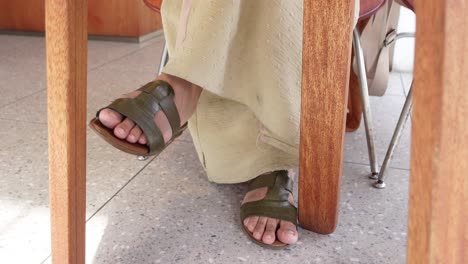 woman sitting at a cafe table with legs and feet visible