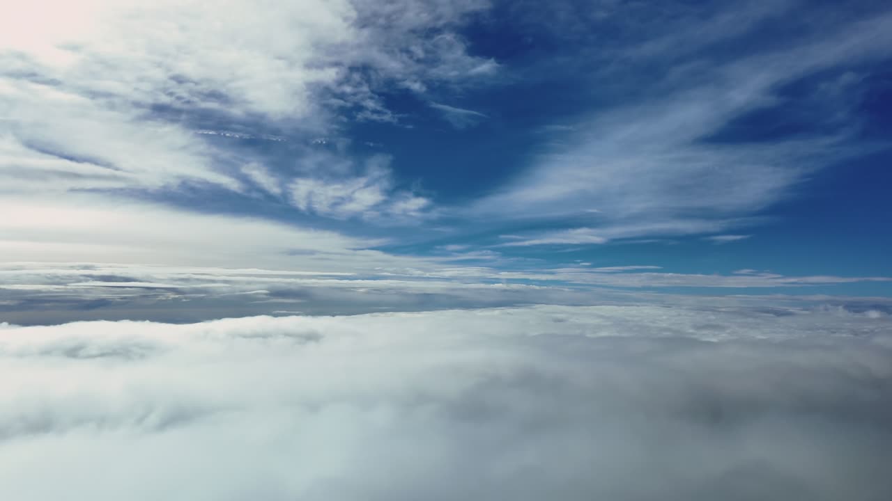 An immersive pilot’s view from the cockpit of a jet flying at supersonic speed descending through layers of fluffy clouds under a blue sky